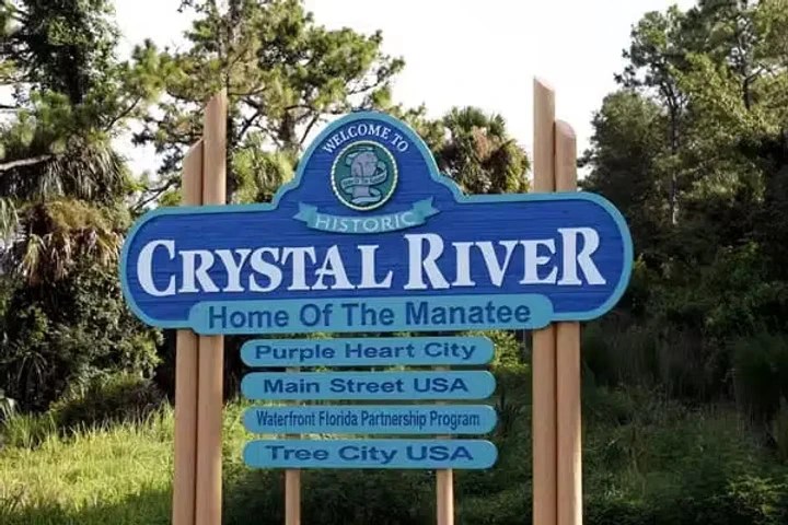 Sign for Crystal River, welcome messages, surrounded by trees.