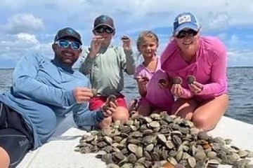 Group of four people on a boat holding seashells with a pile in front.