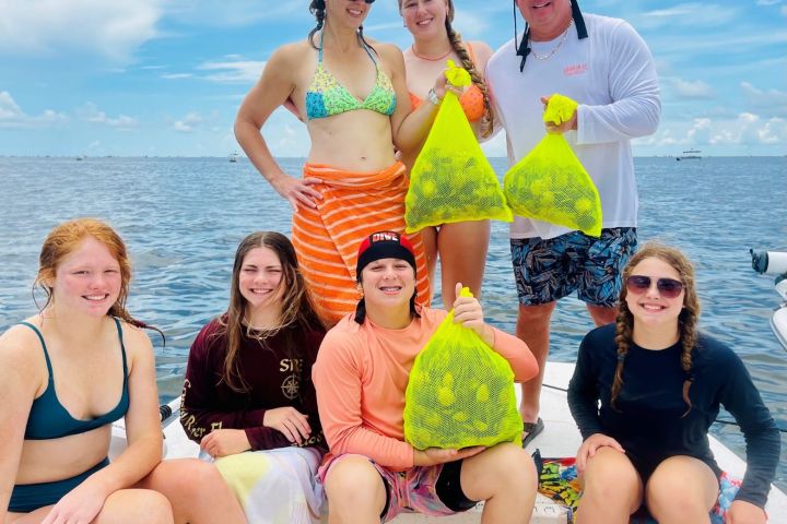 Group of people on a boat holding bags with water in the background.