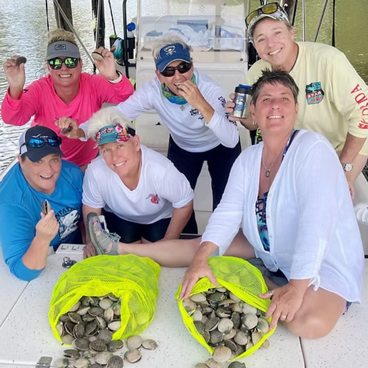Group of six people on a boat with bags of collected shells.